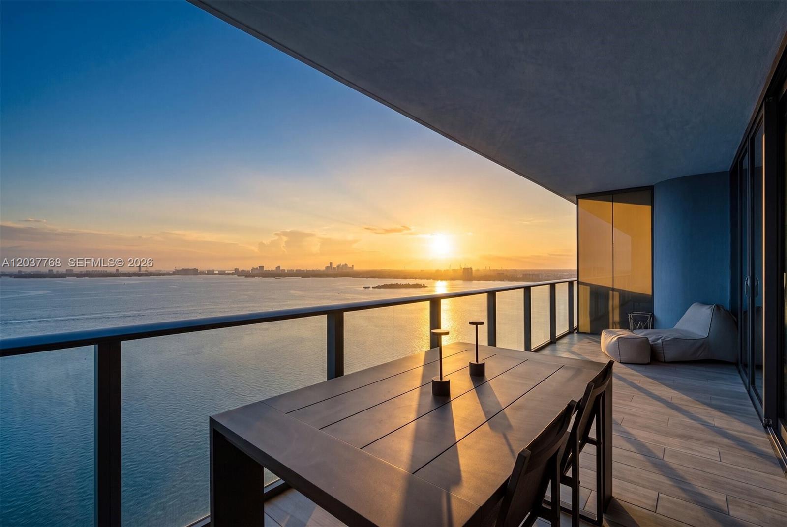A modern kitchen features a stone island, dark wood cabinetry, and floor-to-ceiling windows with ocean views — 3131 NE 7th Ave # 2402, Miami FL 33137, MIAMI, FL
