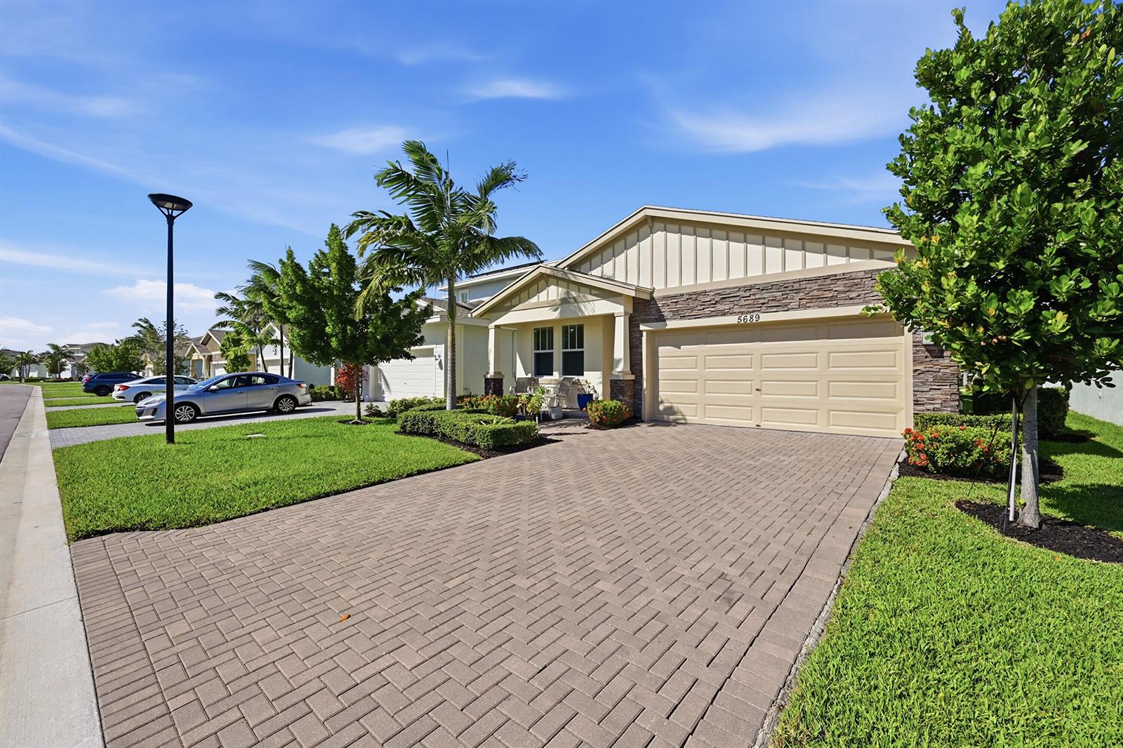 A single-story house with a stone facade, beige garage, and a paved driveway — 5689 Graceful Way, Delray Beach FL 33484, DELRAY BEACH, FL