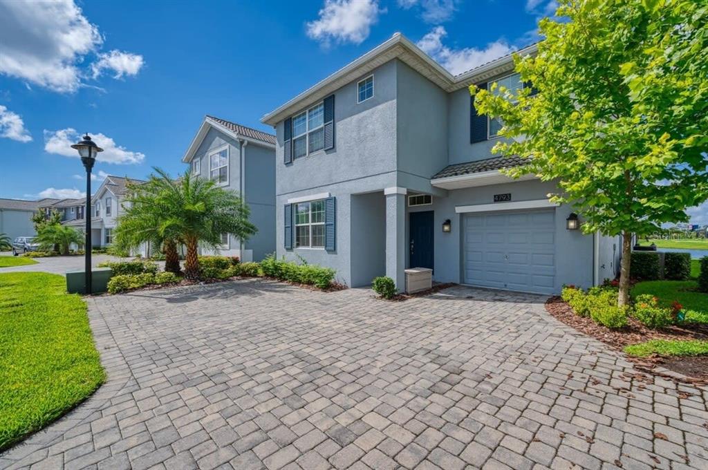 A two-story gray stucco townhouse with a paved driveway, a garage, and a front entrance — 4793 KINGS CASTLE CIRCLE, KISSIMMEE, FL