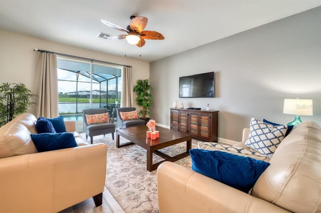 A living room features beige leather sofas, a wooden coffee table, and a sliding glass door — 4793 KINGS CASTLE CIRCLE, KISSIMMEE, FL