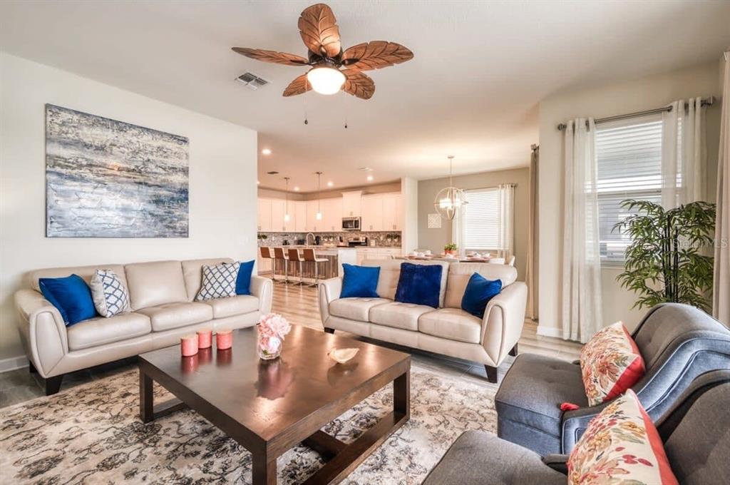 A living room features two beige sofas, a wooden coffee table, and a ceiling fan — 4793 KINGS CASTLE CIRCLE, KISSIMMEE, FL