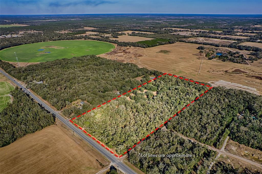 An aerial view shows a rectangular wooded lot outlined in red along a paved road — S US HWY 129, BELL, FL
