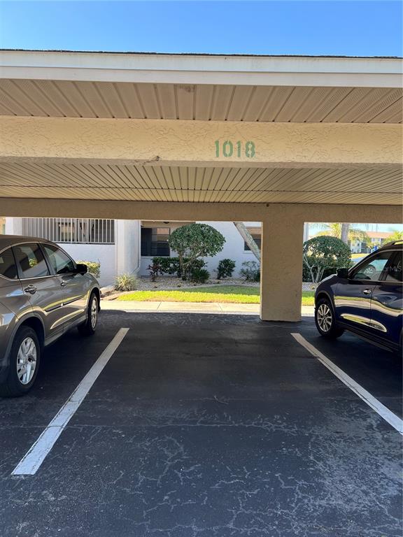 A covered parking area features two parked cars and the number 1018 on the beam — 175 KINGS HIGHWAY UNIT A8, PUNTA GORDA, FL
