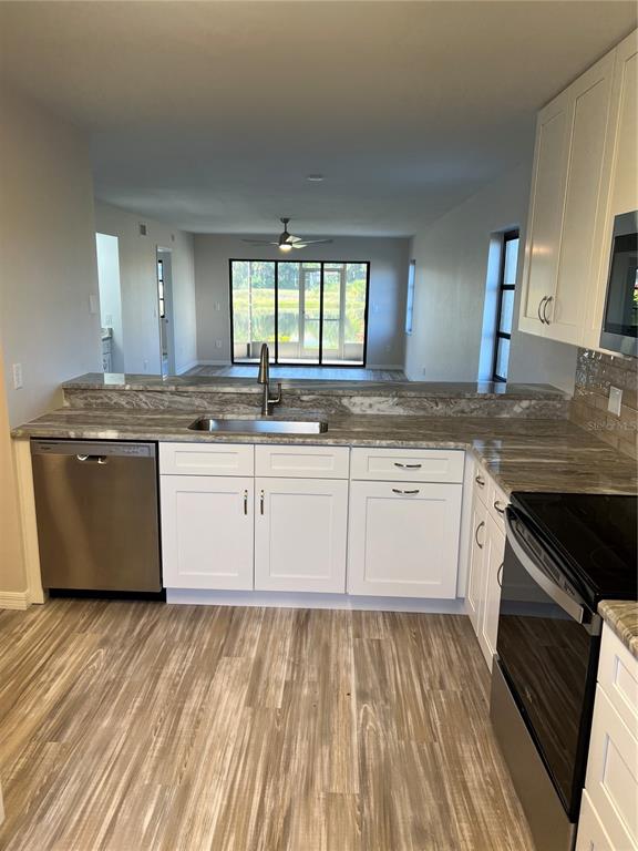 A kitchen with white cabinets, stone countertops, stainless steel appliances, and a view of water — 175 KINGS HIGHWAY UNIT A8, PUNTA GORDA, FL
