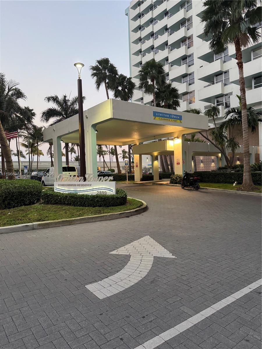 The exterior entrance of a condominium building features a covered driveway and a paved road — 2899 Collins Ave # 936, Miami Beach FL 33140, MIAMI BEACH, FL