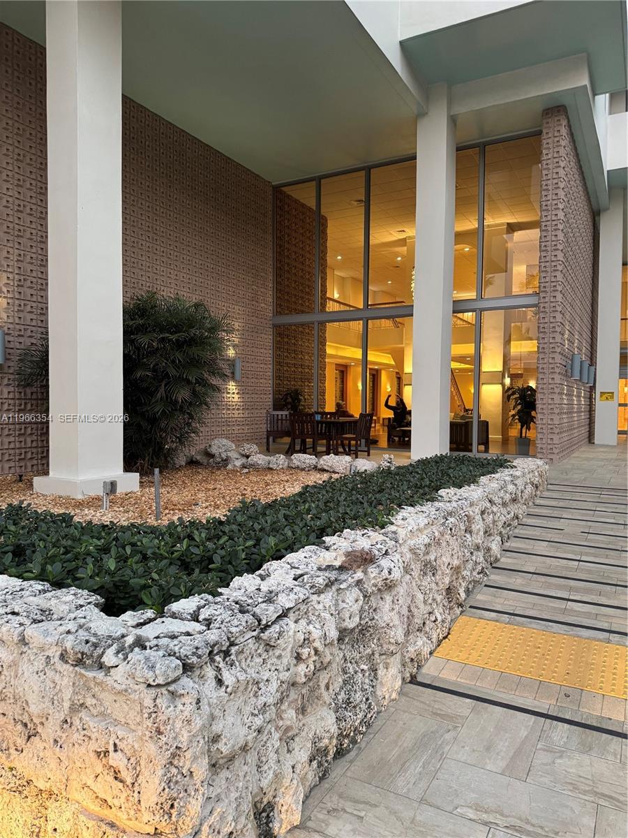 An exterior view of a building entrance featuring a stone planter and large glass windows — 2899 Collins Ave # 936, Miami Beach FL 33140, MIAMI BEACH, FL