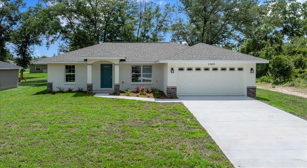 A single-story house with a white stucco exterior, a two-car garage, and a front porch — 13413 SE 101ST TERRACE, BELLEVIEW, FL