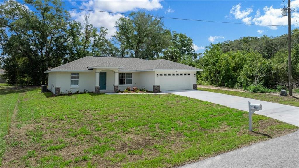 A single-story house with a white stucco exterior, a two-car garage, and a front lawn — 13413 SE 101ST TERRACE, BELLEVIEW, FL