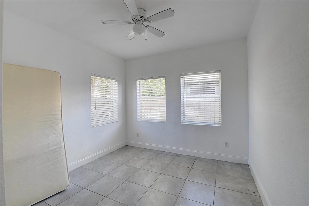 An empty room with white walls, gray tile flooring, three windows, and a ceiling fan — 707 SW 9th Court, Delray Beach FL 33444, DELRAY BEACH, FL