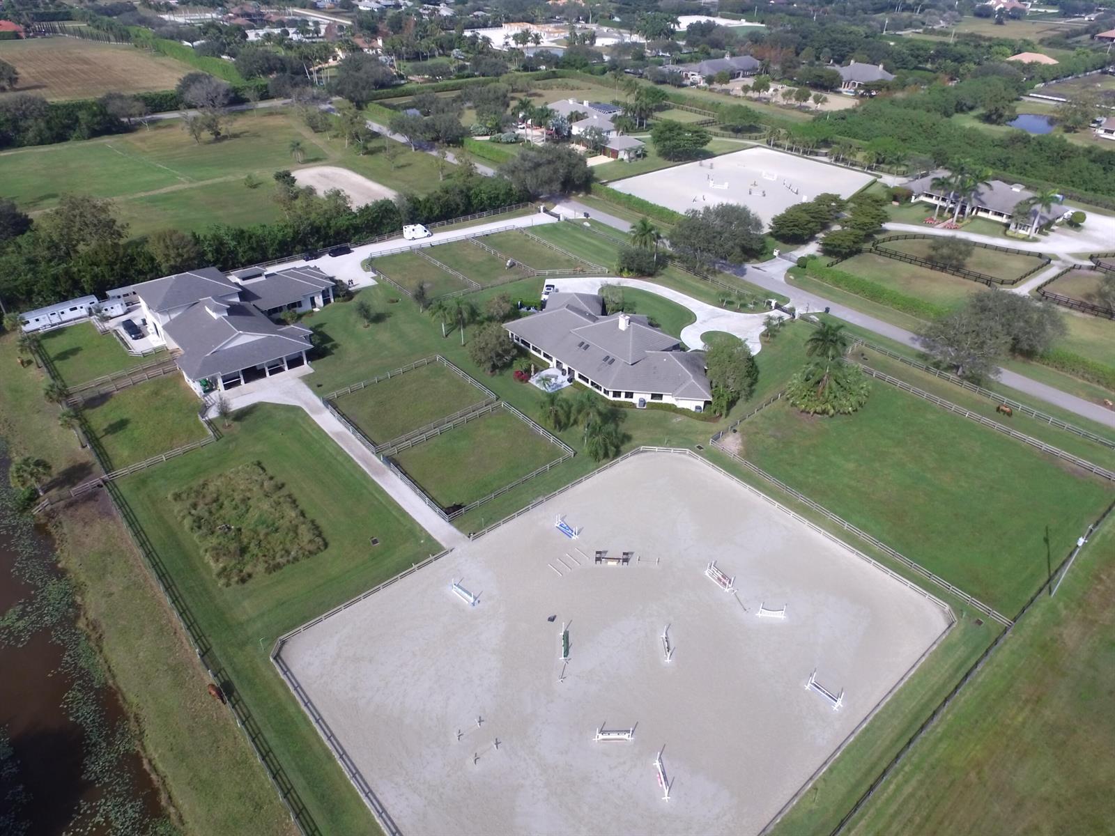 An aerial view shows a horse farm with two large buildings, paddocks, and riding arenas — 15450 Estancia Lane, Wellington FL 33414, WELLINGTON, FL