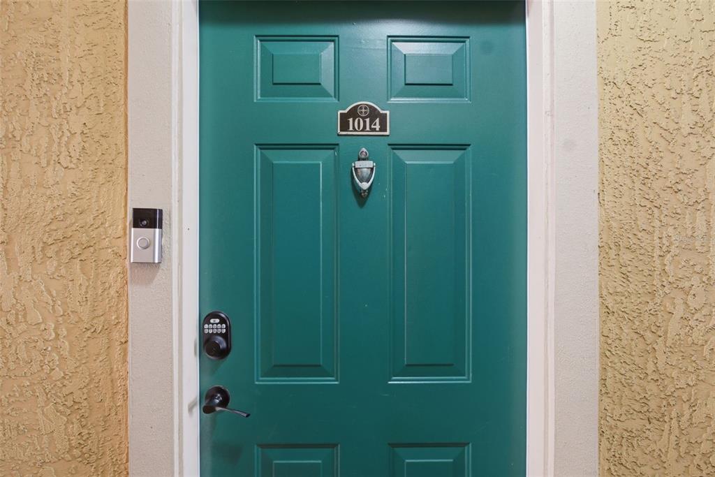 A teal front door with a digital keypad, doorbell camera, and number 1014 plaque — 2739 VIA CAPRI UNIT 1014, CLEARWATER, FL
