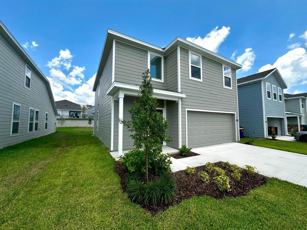 A two-story gray house with a two-car garage and a small front yard — 3129 BROOKHOLLOW WAY, MINNEOLA, FL
