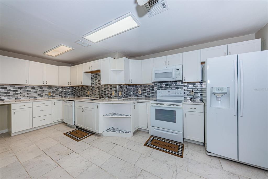 A kitchen with white cabinets, white appliances, and a gray and white tiled backsplash — 8419 125TH PLACE, LARGO, FL