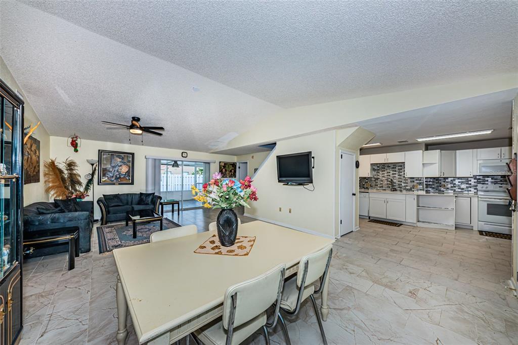 A dining area opens into a living room and kitchen with tile floors and vaulted ceilings — 8419 125TH PLACE, LARGO, FL