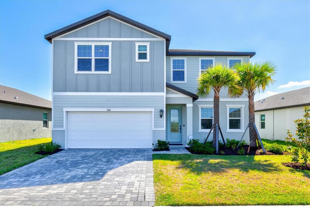 A two-story house with light blue siding, a two-car garage, and two palm trees — 506 SUN CHASER DRIVE, NOKOMIS, FL