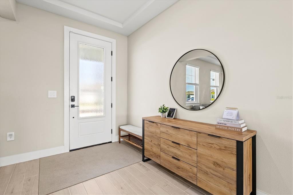 An entryway features a white front door, a wooden console table, and a round mirror — 506 SUN CHASER DRIVE, NOKOMIS, FL