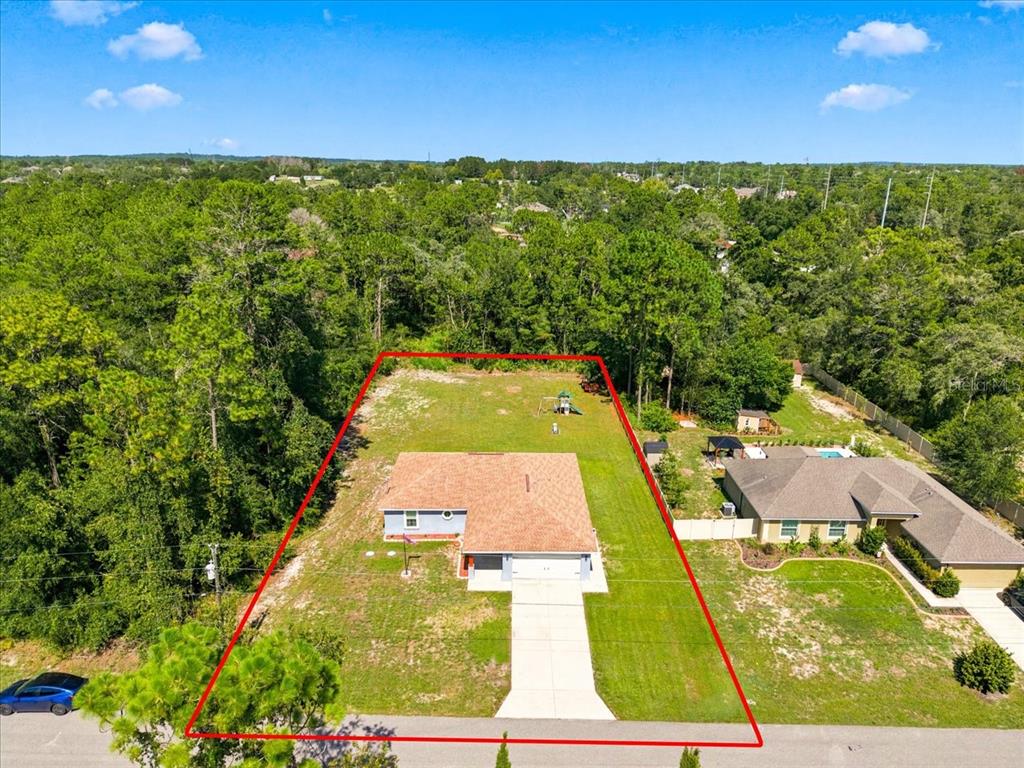 An aerial view shows a single-story house with a large backyard enclosed by red lines — 12327 MILLINGTON AVENUE, WEEKI WACHEE, FL
