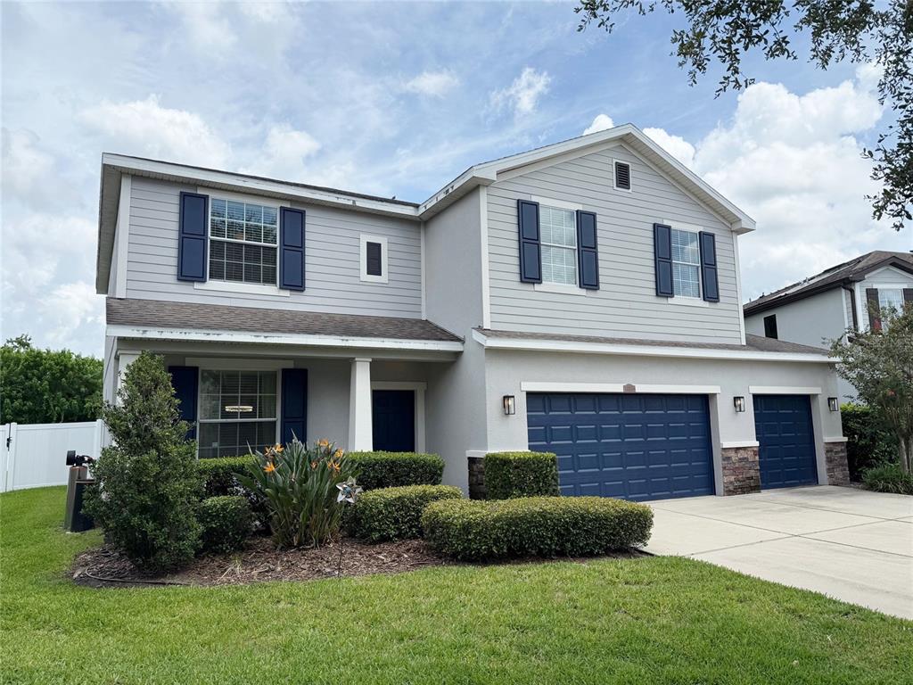 A two-story suburban house with light gray siding, blue shutters, and a three-car garage — 12236 FAIRLAWN DRIVE, RIVERVIEW, FL