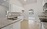 A kitchen features white cabinets, granite countertops, a double sink, and tile flooring — 247 SW BELLFLOWER DRIVE, LAKE CITY, FL