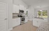 A kitchen features white cabinets, stainless steel appliances, granite countertops, and a center island — 247 SW BELLFLOWER DRIVE, LAKE CITY, FL