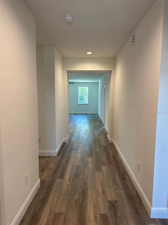 A hallway with wood-look flooring leads toward a room with a window — 519 ELLIE COURT, APOPKA, FL