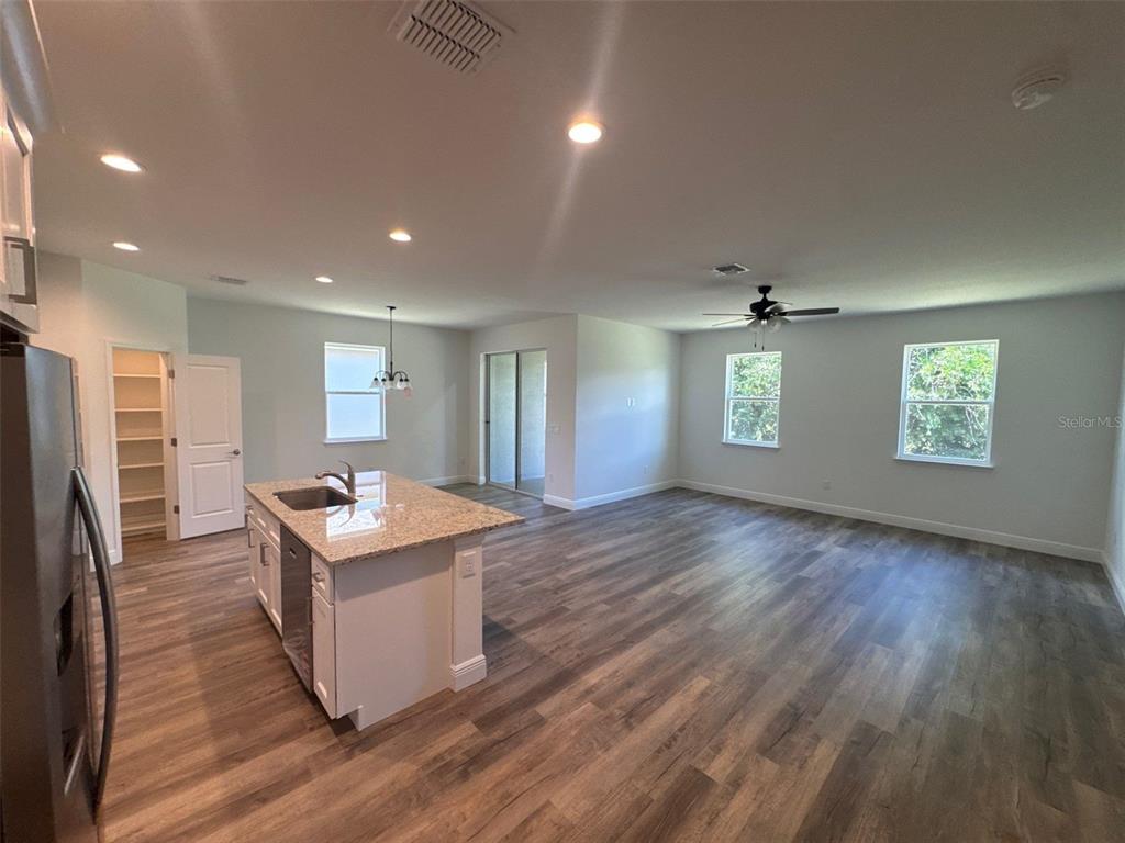 A kitchen with a granite island and white cabinets opens into a spacious living area — 519 ELLIE COURT, APOPKA, FL