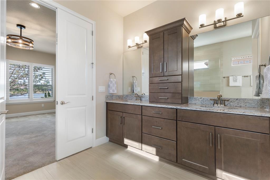 A bathroom features a double vanity with dark wood cabinets, granite countertops, and a mirror — 661 MAHOGANY RUN, PALM COAST, FL
