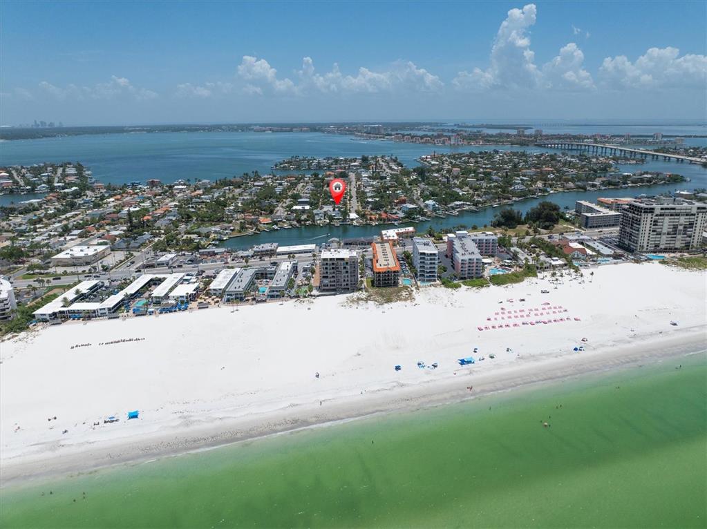 An aerial view shows a sandy beach, coastal buildings, and a residential neighborhood with a canal — 150 42ND AVENUE, ST PETE BEACH, FL