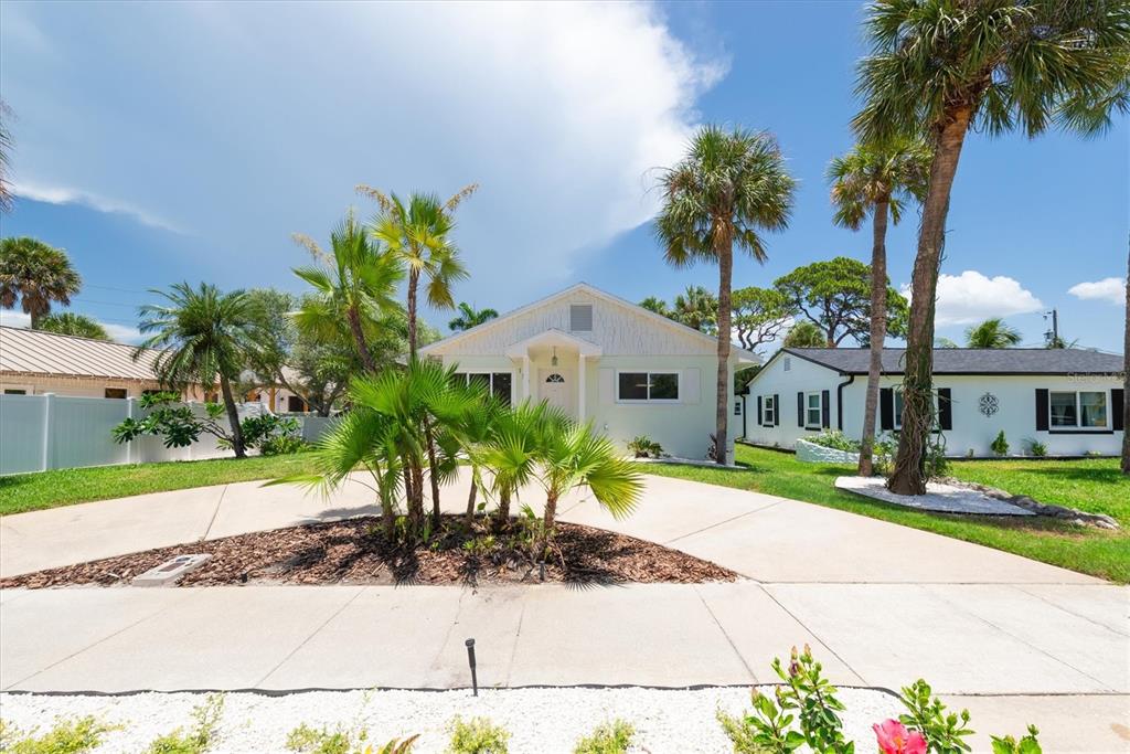 A light-colored house with a palm-filled front yard and a concrete driveway — 150 42ND AVENUE, ST PETE BEACH, FL