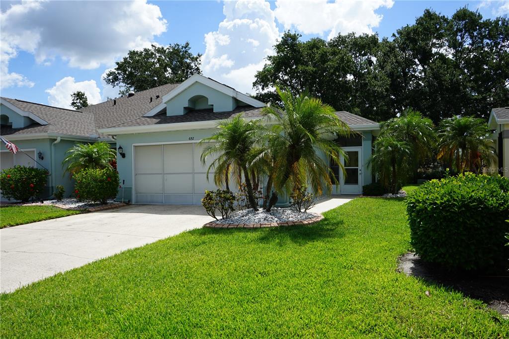 A single-story house with a white garage, palm trees, and a green lawn — 652 MC DANIEL STREET UNIT 90, SUN CITY CENTER, FL