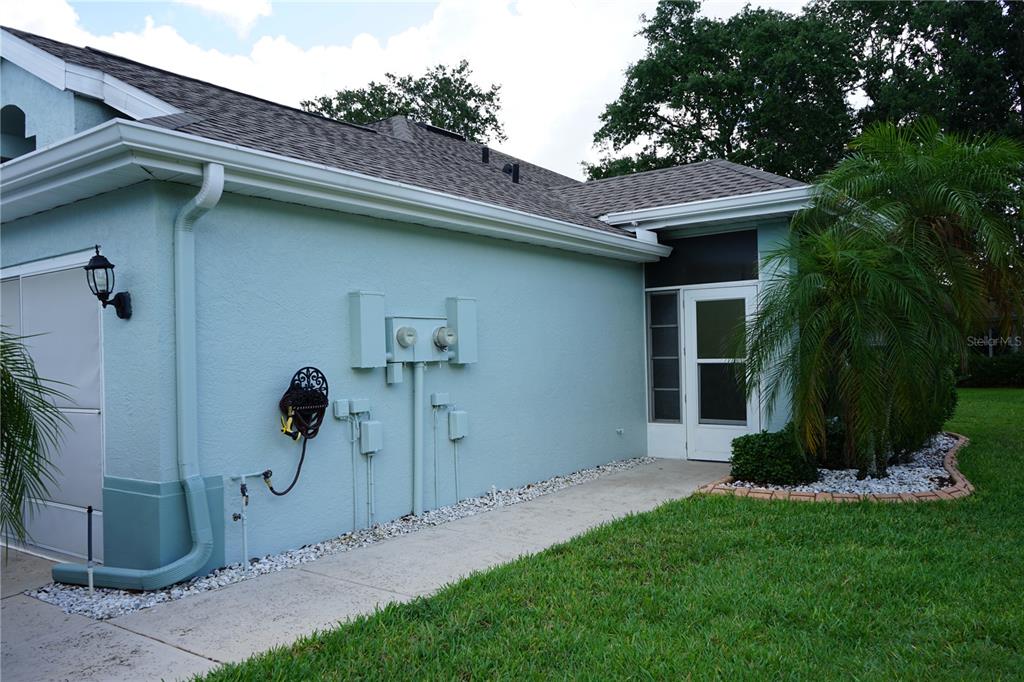 A light blue house exterior features a concrete walkway, a screen door, and utility meters — 652 MC DANIEL STREET UNIT 90, SUN CITY CENTER, FL