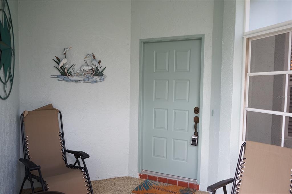 A light green front door with a lockbox sits on a porch with two chairs — 652 MC DANIEL STREET UNIT 90, SUN CITY CENTER, FL