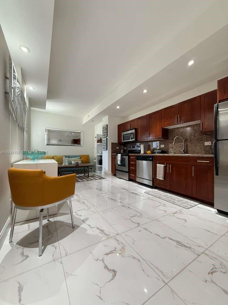 A modern kitchen with dark wood cabinets and white marble floors opens into a living area — 111 E Flagler St # 806, Miami FL 33131, MIAMI, FL