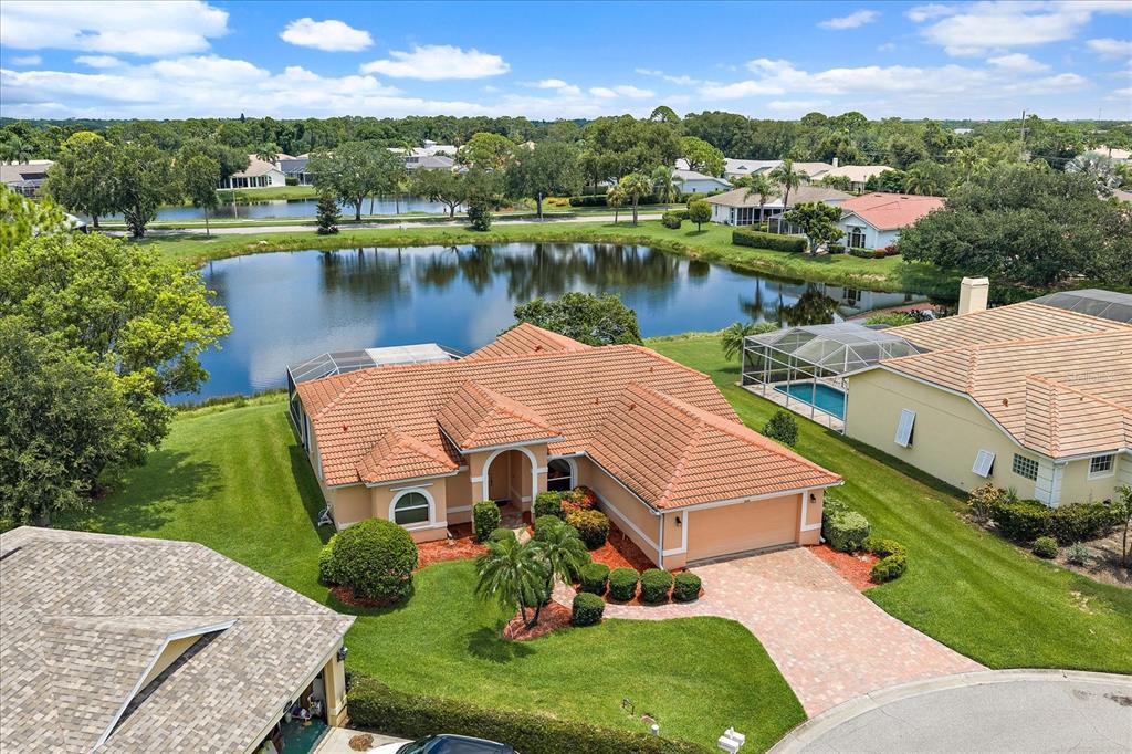 An aerial view of a single-story house with a tile roof, pool, and lakefront backyard — 9539 HAWKSMOOR LANE, SARASOTA, FL