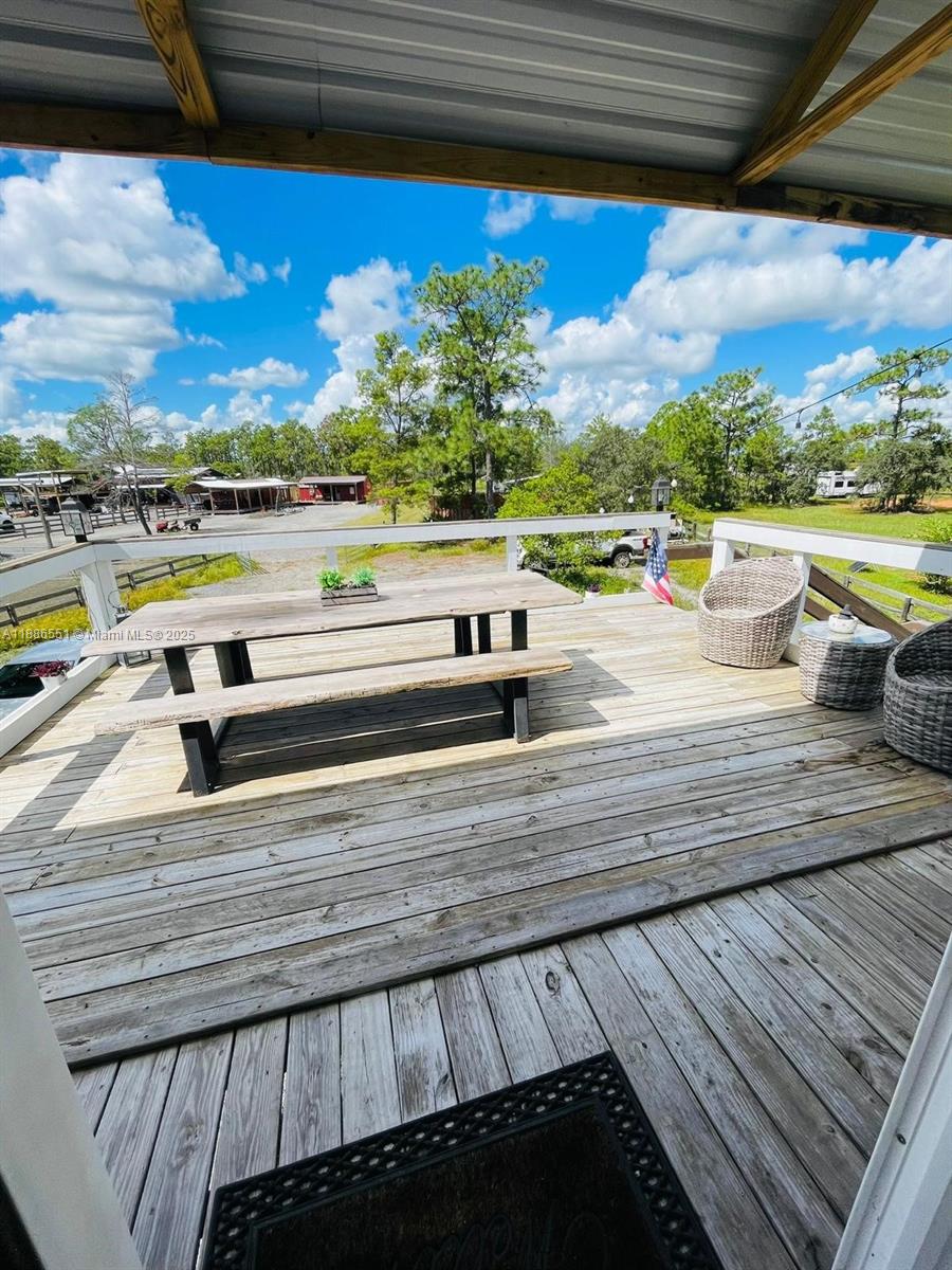 A wooden deck features a picnic table, wicker chairs, and a railing overlooking a yard — 0 Highway 630 E, Frostproof FL 33843, FROSTPROOF, FL