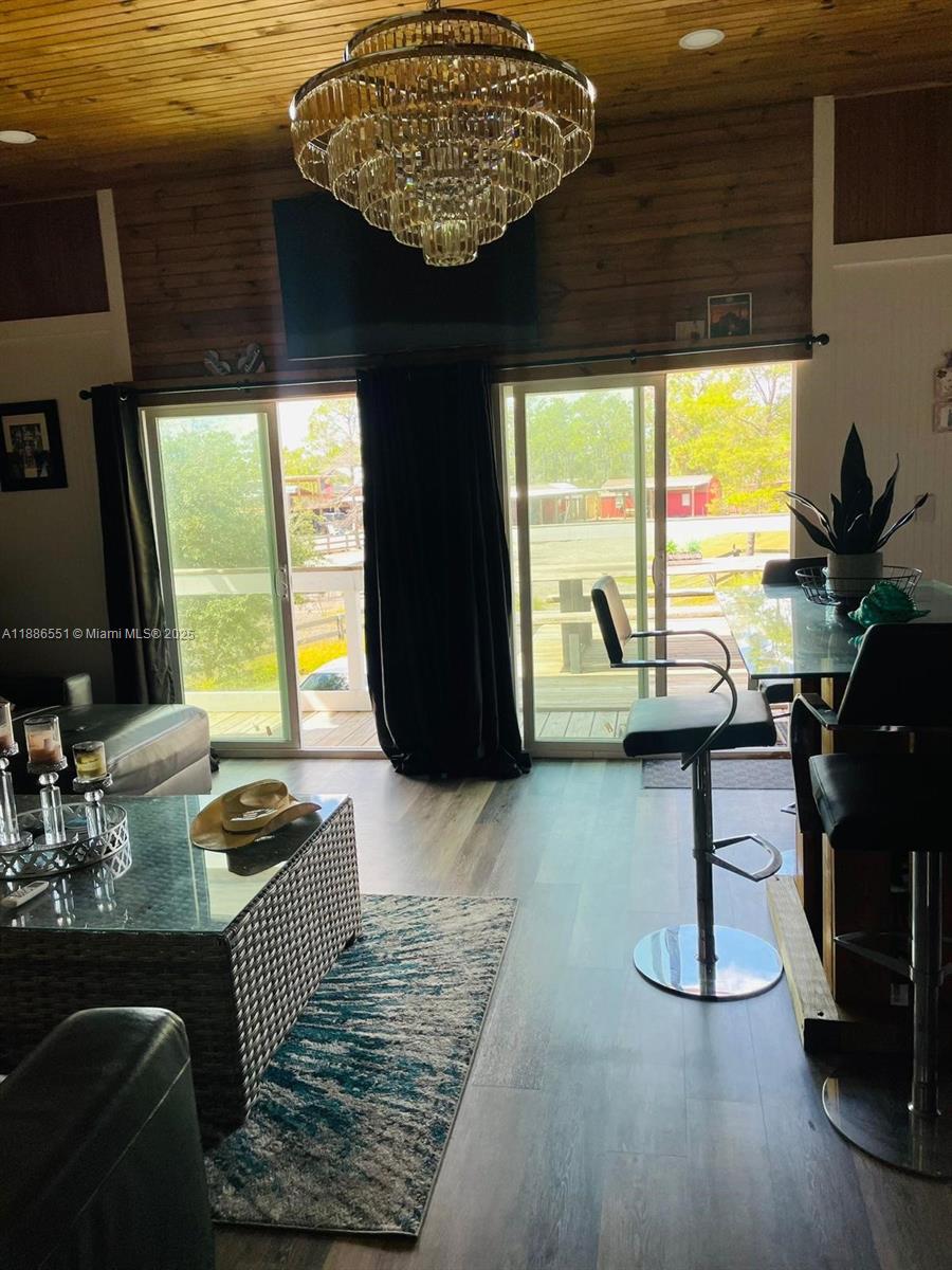 A living room features a crystal chandelier, wood-paneled ceiling, and sliding glass doors to a deck — 0 Highway 630 E, Frostproof FL 33843, FROSTPROOF, FL