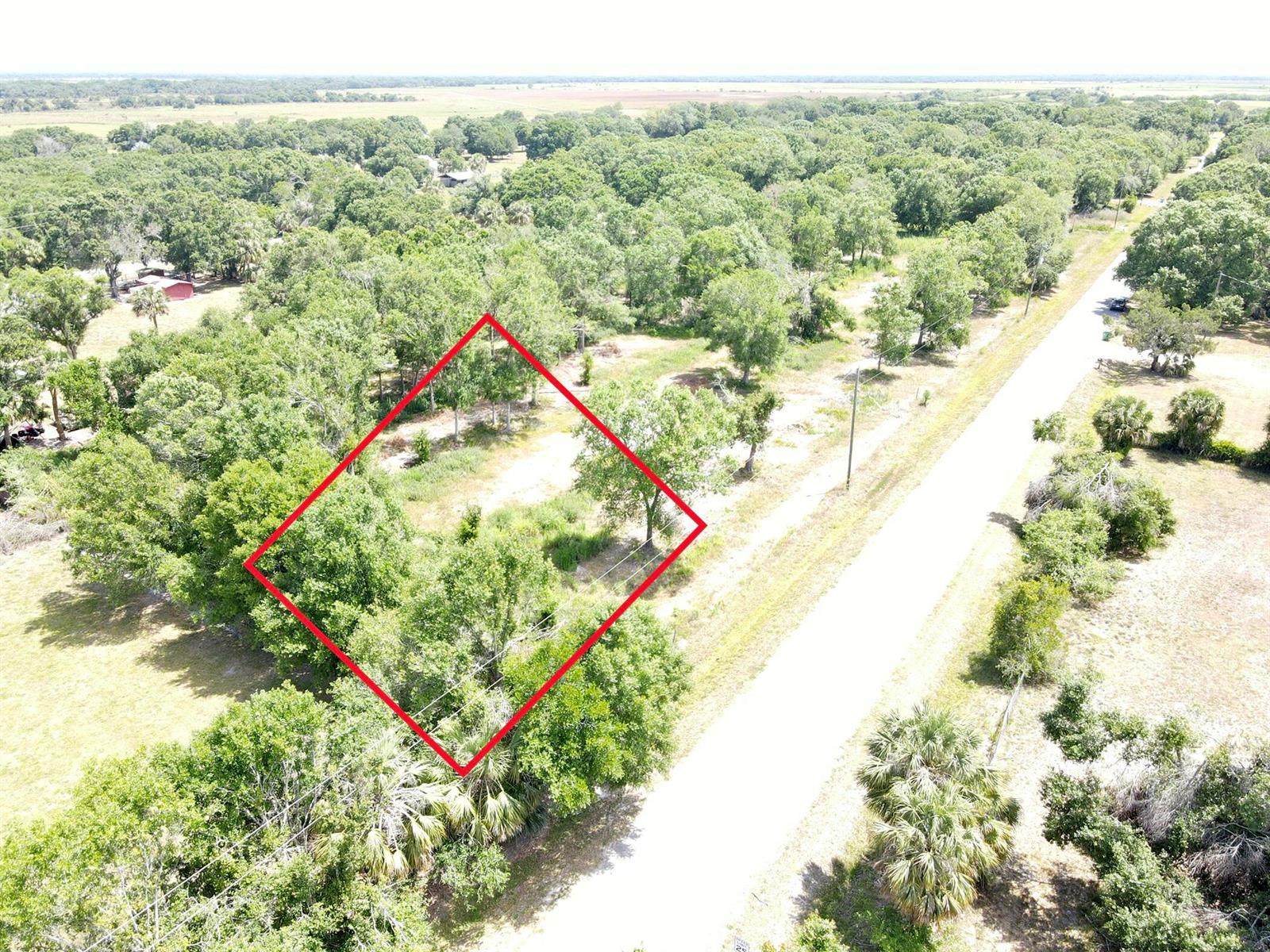 An aerial view shows a rectangular plot of land outlined in red beside a road — 7877 NW 93rd Court, Okeechobee FL 34972, OKEECHOBEE, FL
