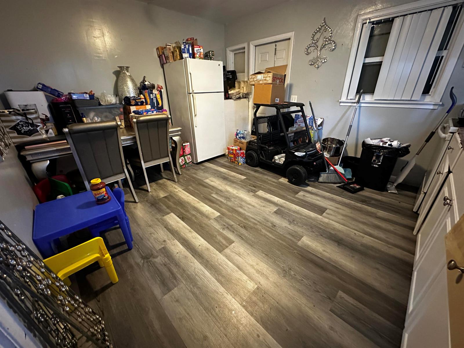 A kitchen area features wood-look flooring, a white refrigerator, a dining set, and a toy vehicle — 566 SE 7th Drive, Belle Glade FL 33430, BELLE GLADE, FL