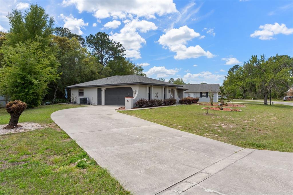 A single-story house with a concrete driveway, a two-car garage, and a large front lawn — 5 MANGROVE COURT S, HOMOSASSA, FL