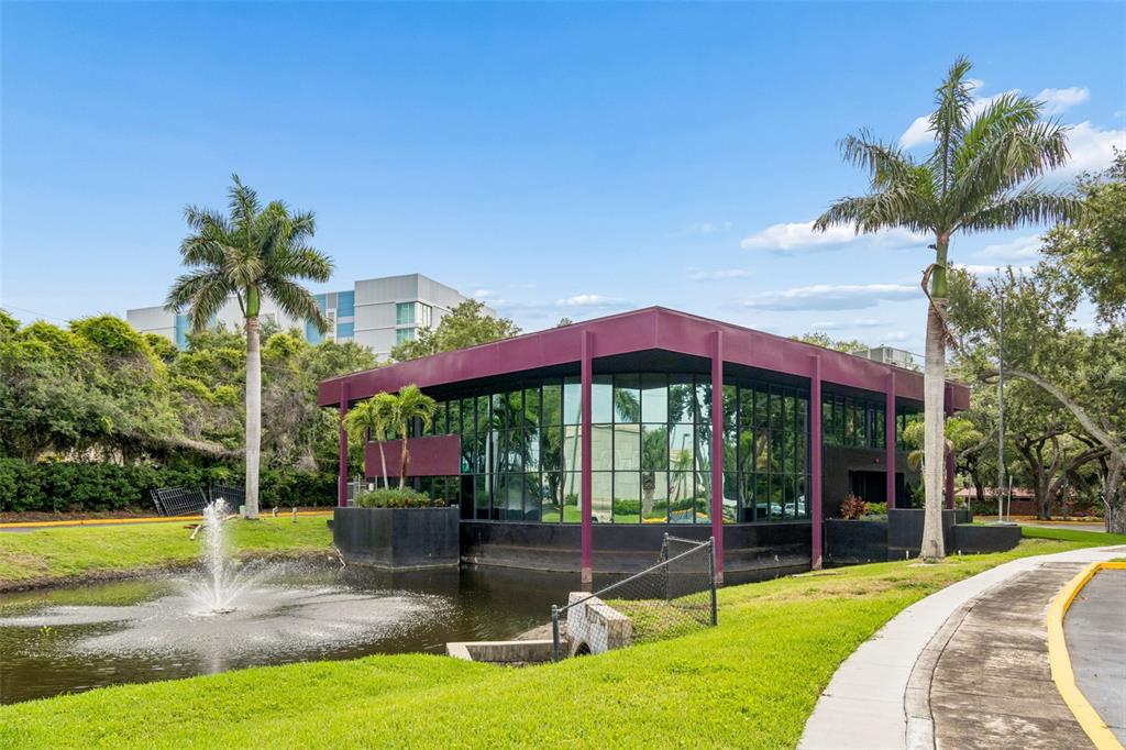 A modern office building with glass walls sits beside a pond with a fountain — 19995 US HIGHWAY 19 N, CLEARWATER, FL