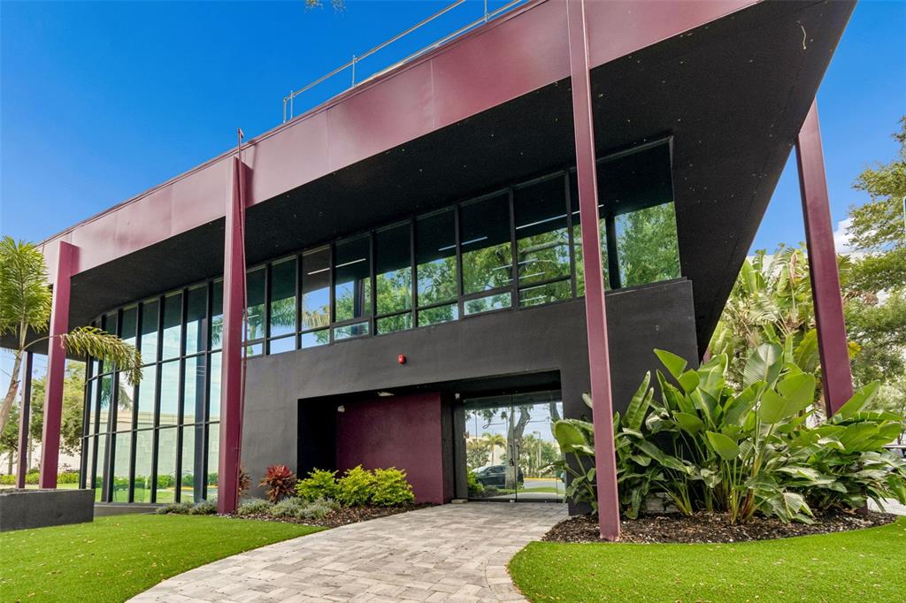 A modern two-story building with dark exterior walls, large glass windows, and a paved walkway — 19995 US HIGHWAY 19 N, CLEARWATER, FL