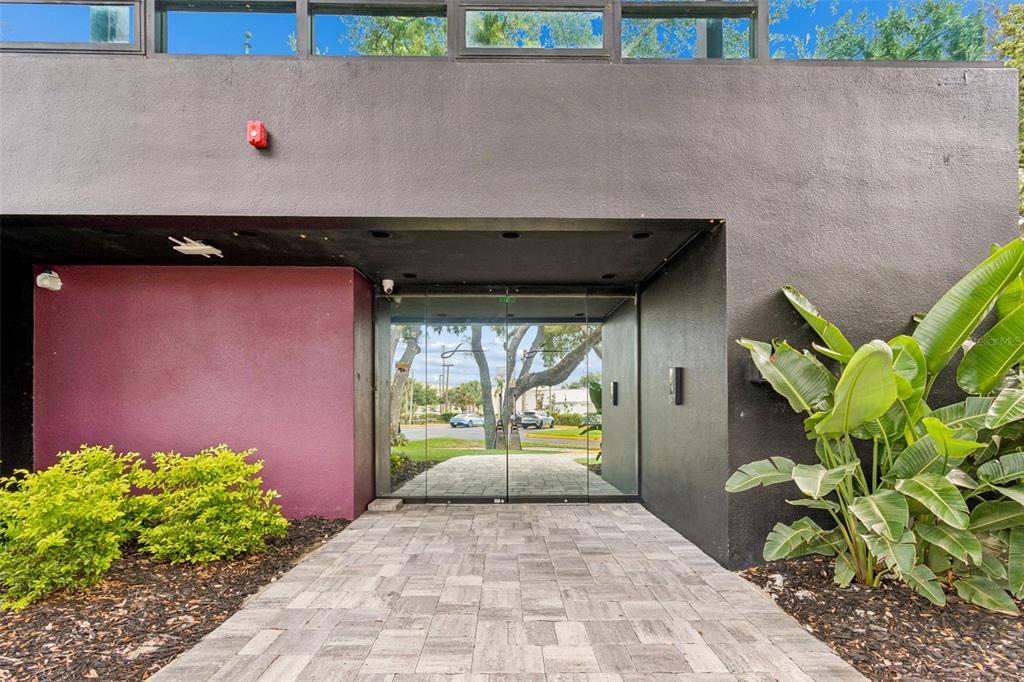 A paved walkway leads to a glass-paneled entrance framed by dark gray and purple walls — 19995 US HIGHWAY 19 N, CLEARWATER, FL