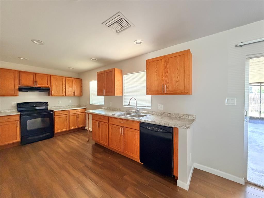 A kitchen features wood cabinets, black appliances, laminate countertops, and wood-look flooring — 130 S BULOVA DRIVE, APOPKA, FL