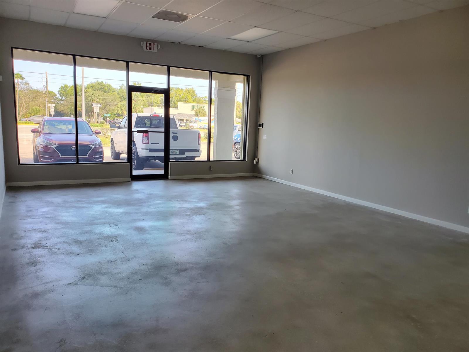 An empty commercial space features a concrete floor, large windows, and a glass entry door — 6366 SE Federal Highway # 6378a, Stuart FL 34997, STUART, FL