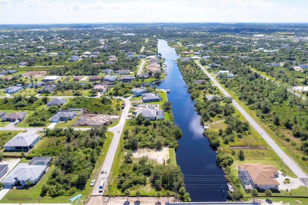 An aerial view shows a canal running through a residential neighborhood with houses and vegetation — 13391 CHENILLE DRIVE, PORT CHARLOTTE, FL