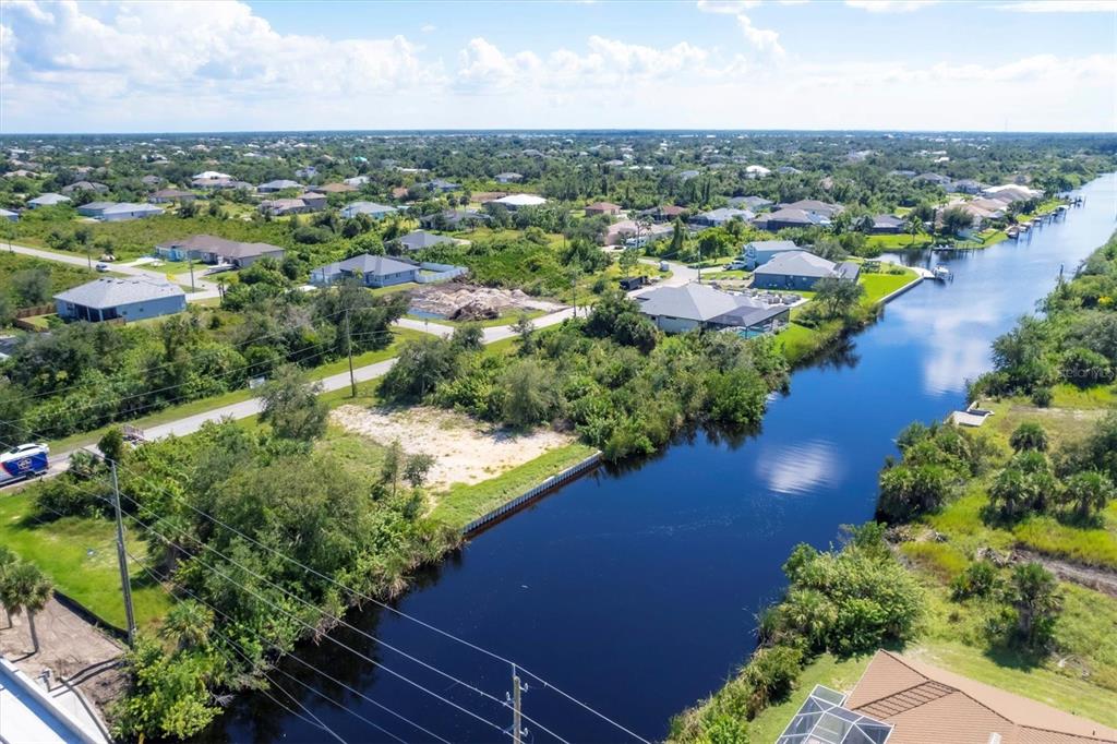 An aerial view shows a vacant waterfront lot bordered by a canal and residential homes — 13391 CHENILLE DRIVE, PORT CHARLOTTE, FL