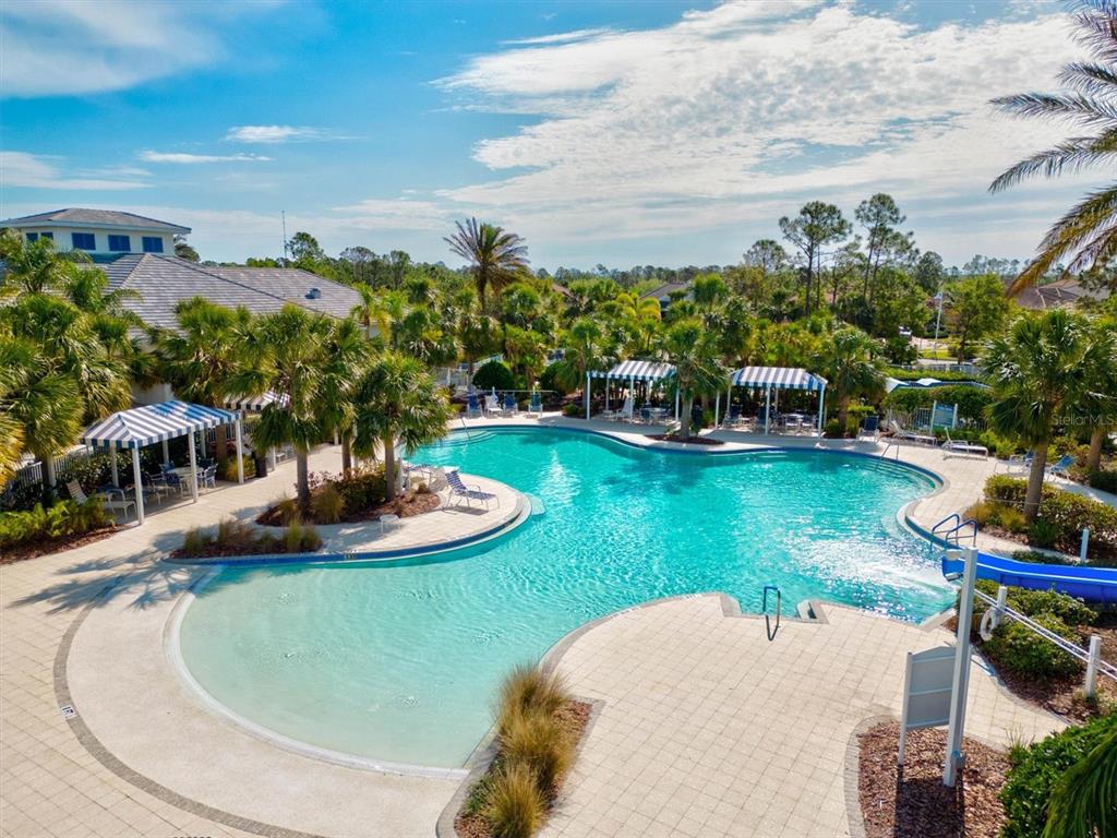 A swimming pool with a blue slide and striped cabanas surrounded by palm trees — 11876 HUNTERS CREEK ROAD, VENICE, FL