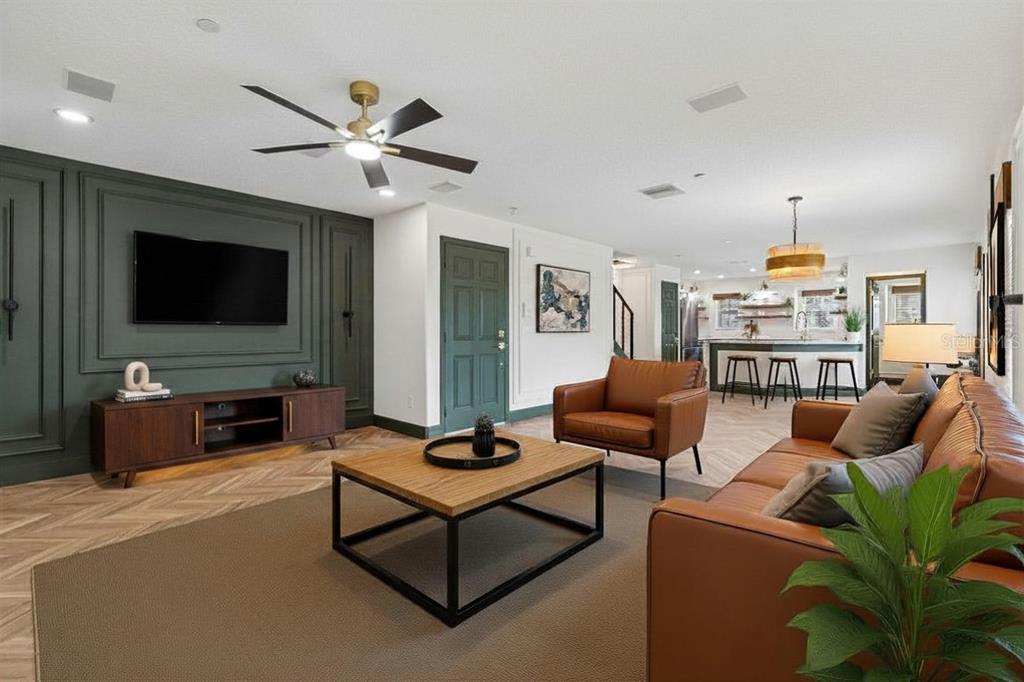 A living room with a dark green accent wall, leather furniture, and herringbone wood flooring — 504 WHEATON TRENT PLACE, TAMPA, FL