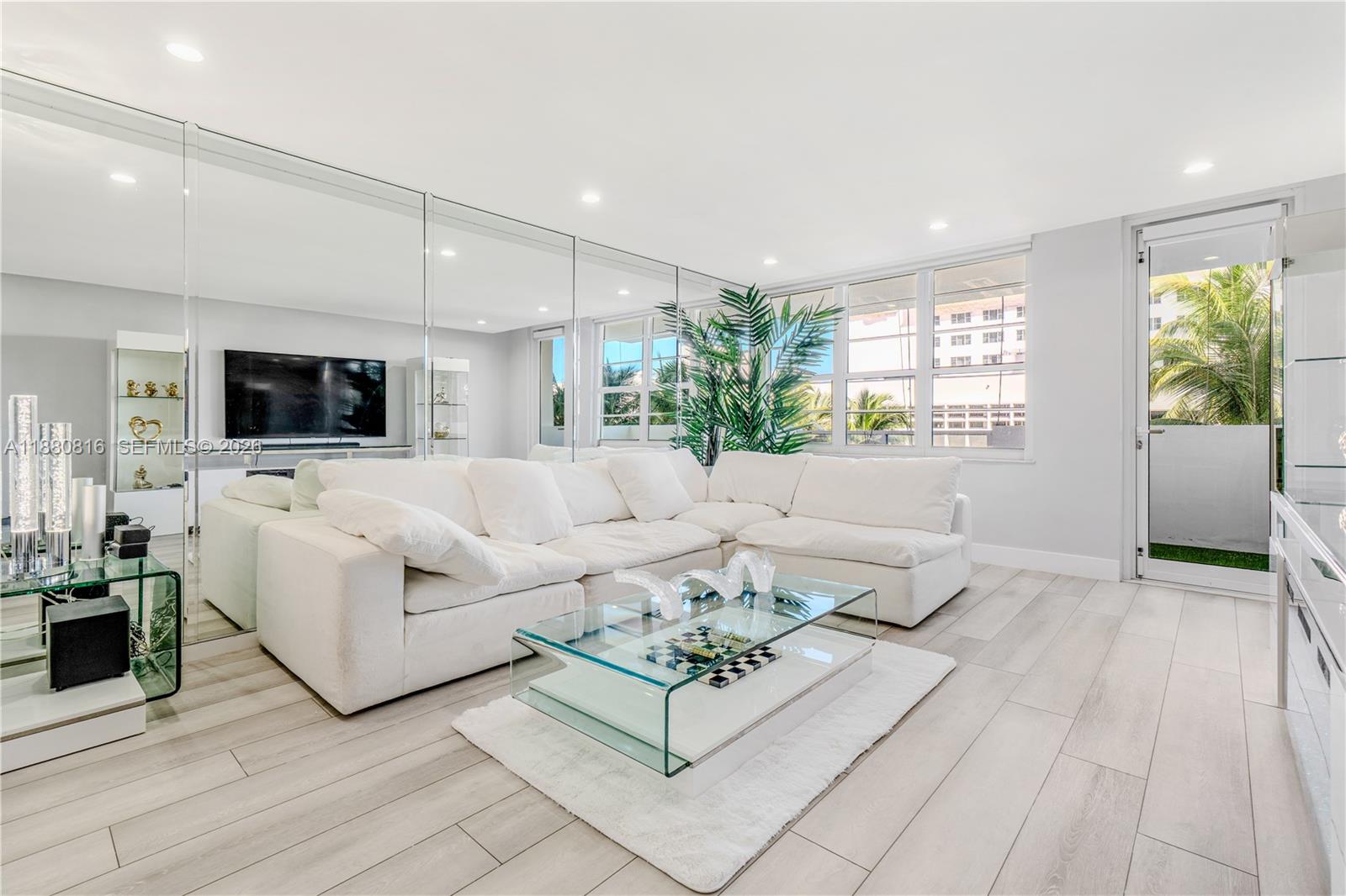A modern, open-concept kitchen and living area features white cabinetry, stainless steel appliances, and flooring — 100 Lincoln Rd # 323, Miami Beach FL 33139, MIAMI BEACH, FL