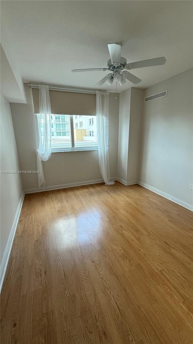 An empty room features light wood flooring, a ceiling fan, and a window with curtains — 1745 E Hallandale Beach Blvd # 306W, Hallandale Beach FL 33009, HALLANDALE BEACH, FL
